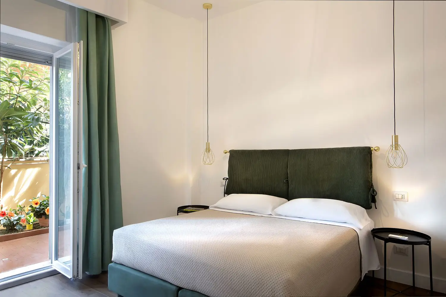 Camera Turandot: letto matrimoniale e portafinestra aperta sul patio con vista giardino